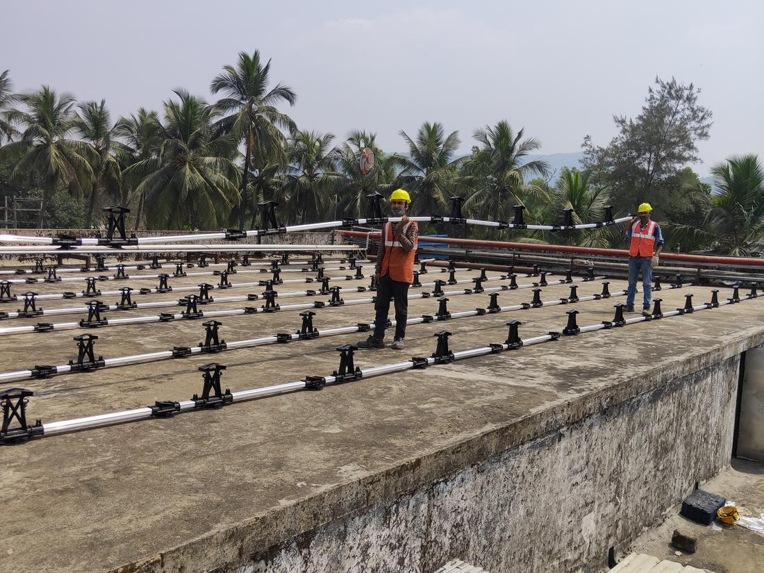Technicians in full body harness fixing solar mounting brackets on a factory roof